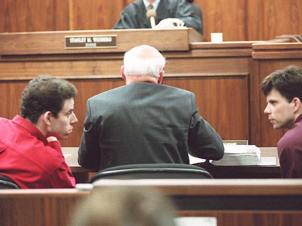 caption: Erik (left) and Lyle Menendez talking in a Los Angeles courtroom on Feb. 2, 1995.
