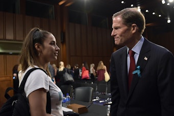 caption: Olympic gold medalist Aly Raisman talks with Sen. Richard Blumenthal, D-Conn., following a 2018 Senate subcommittee hearing on keeping athletes safe from abuse.