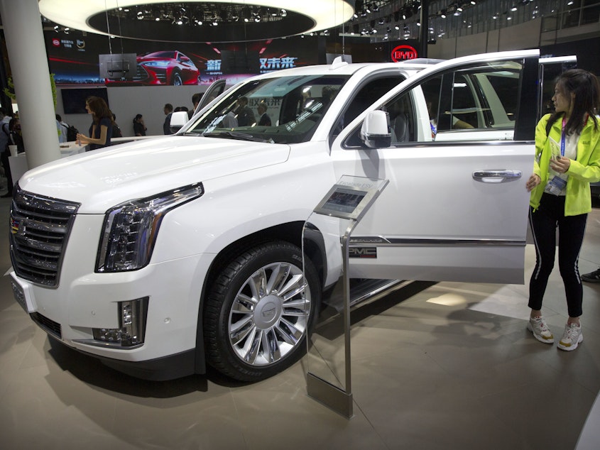 caption: Visitors look at a Cadillac Escalade at the China Auto Show in Beijing in 2018. For General Motors, China is a bigger market than the United States.