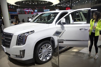 caption: Visitors look at a Cadillac Escalade at the China Auto Show in Beijing in 2018. For General Motors, China is a bigger market than the United States.