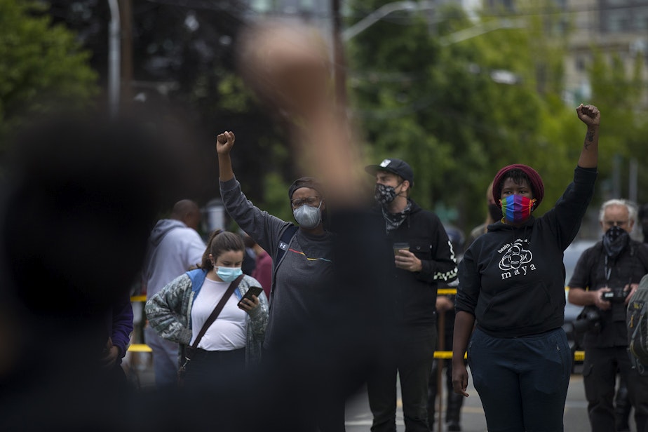 caption: Protesters, including Elisha Ewing, right, raise their fists in the air while forming a circle and blocking traffic at the intersection of Broadway and East Pine Street after Seattle Police Department officers cleared the Capitol Hill Organized Protest zone, CHOP, early on Wednesday, July 1, 2020, in Seattle.