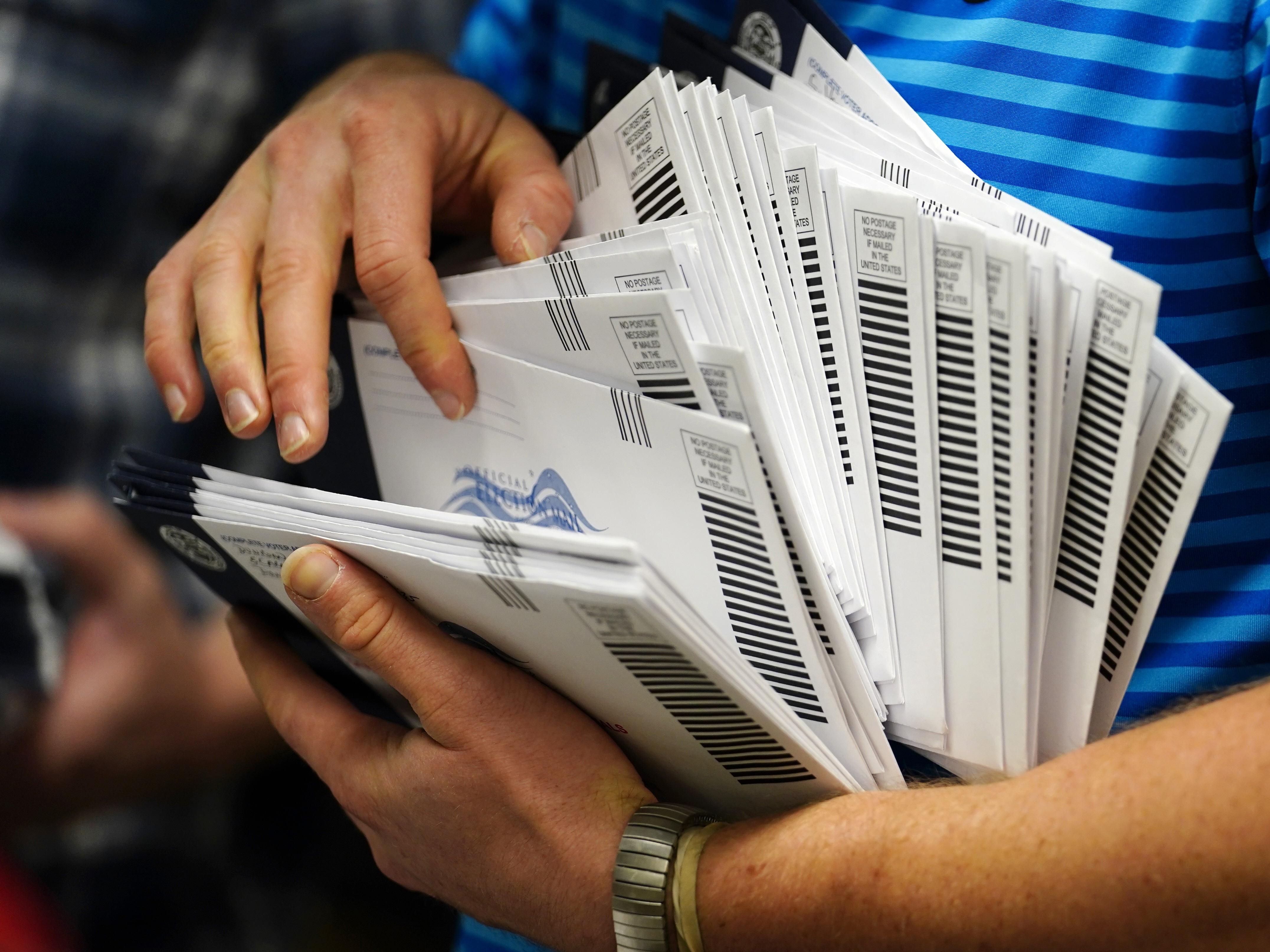 caption: An election official organizes mail-in ballots to be sorted for the 2020 general election in West Chester, Pa.
