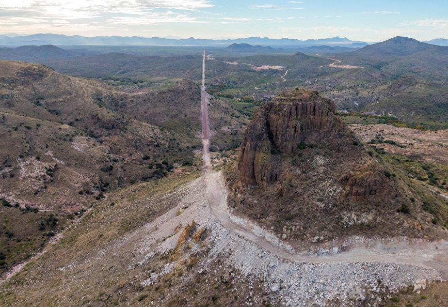 caption: In the Guadalupe Canyon in southeastern Arizona, work crews are dynamiting mountainsides and bulldozing access roads in this stunning landscape to make way for the border wall. Mexico is on the left.