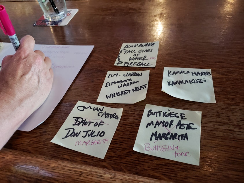 caption: Dana Bos writes up the candidate-themed cocktail names for the Democratic presidential debate on Monday, July 29, 2019.