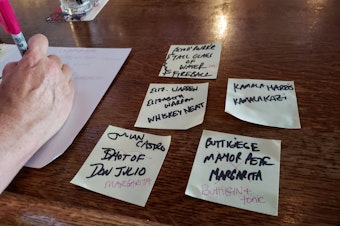 caption: Dana Bos writes up the candidate-themed cocktail names for the Democratic presidential debate on Monday, July 29, 2019.