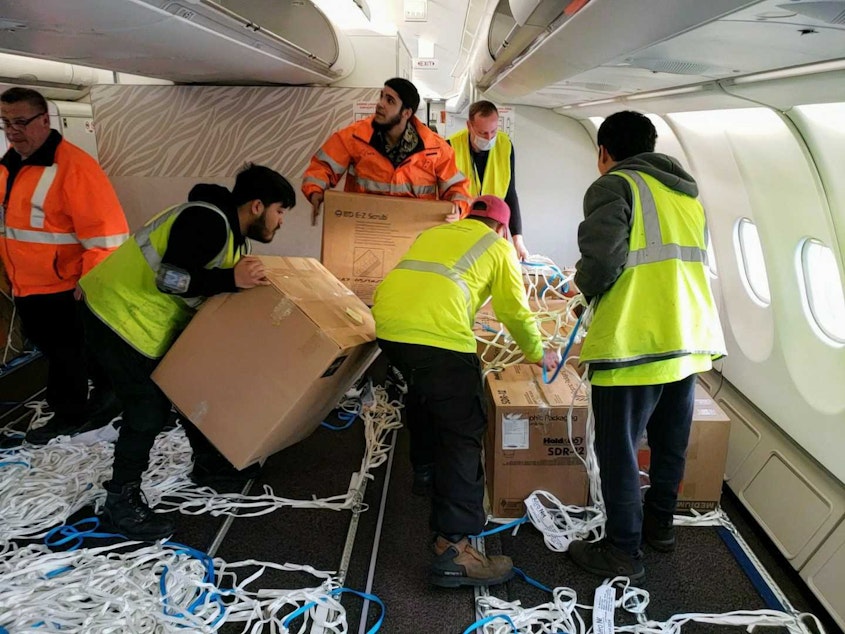 caption: Volunteers packed the jet full of supplies, putting some boxes into the overhead compartments on Monday, March 28, 2022.