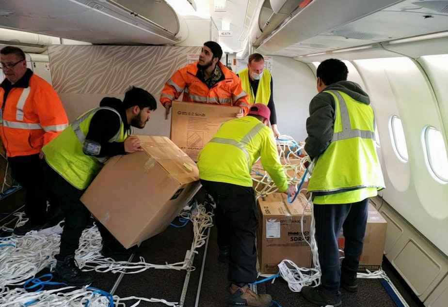 caption: Volunteers packed the jet full of supplies, putting some boxes into the overhead compartments on Monday, March 28, 2022.