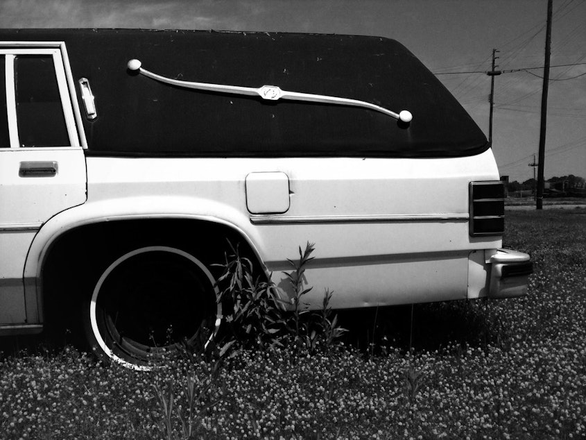 caption: A hearse sits in a field.