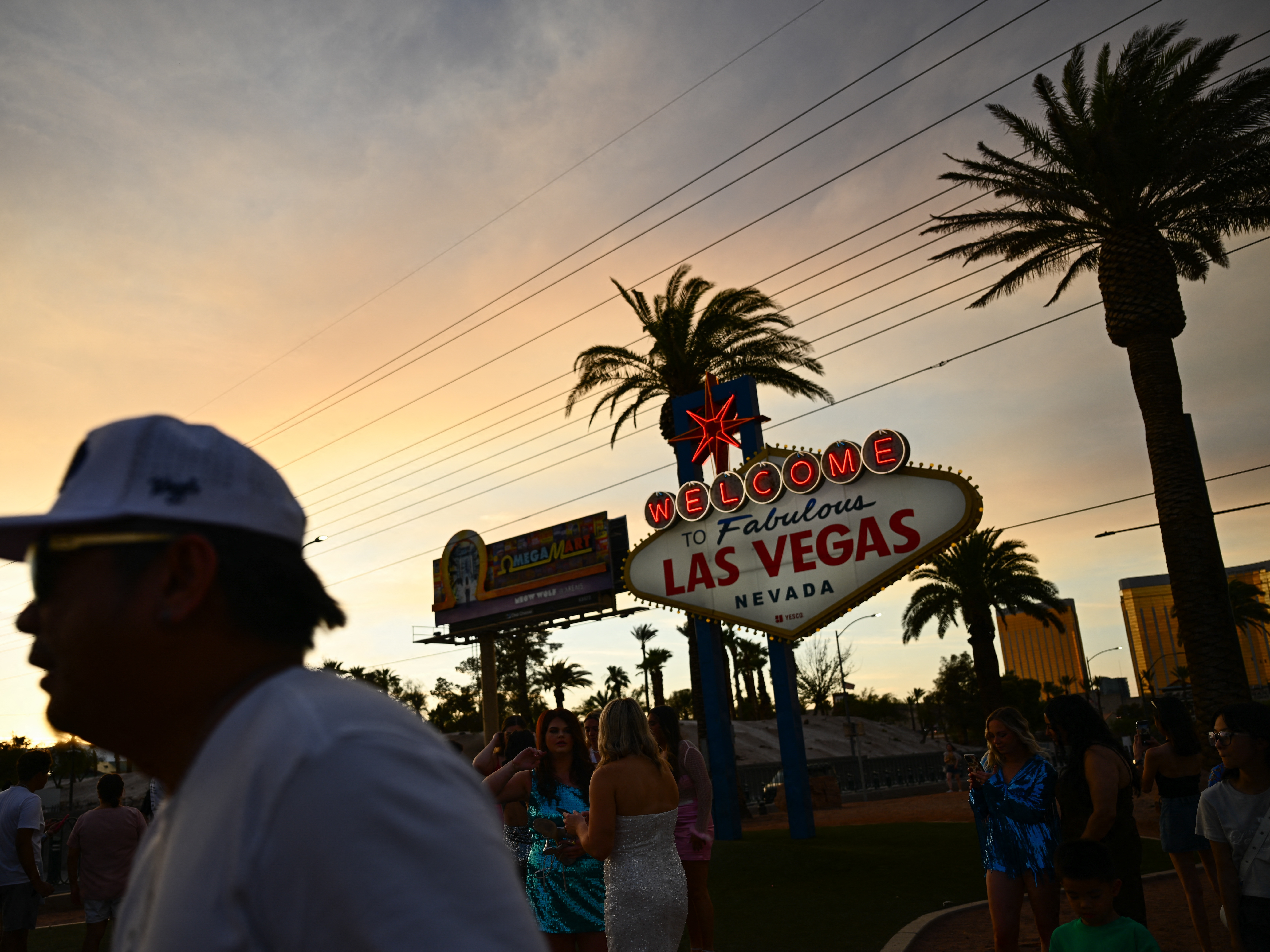 caption: People take pictures with the Las Vegas sign in that city on July 29, 2023. Tourism industry leaders warn that recent actions by the Trump administration may be causing a drop in Canadians traveling to the U.S.
