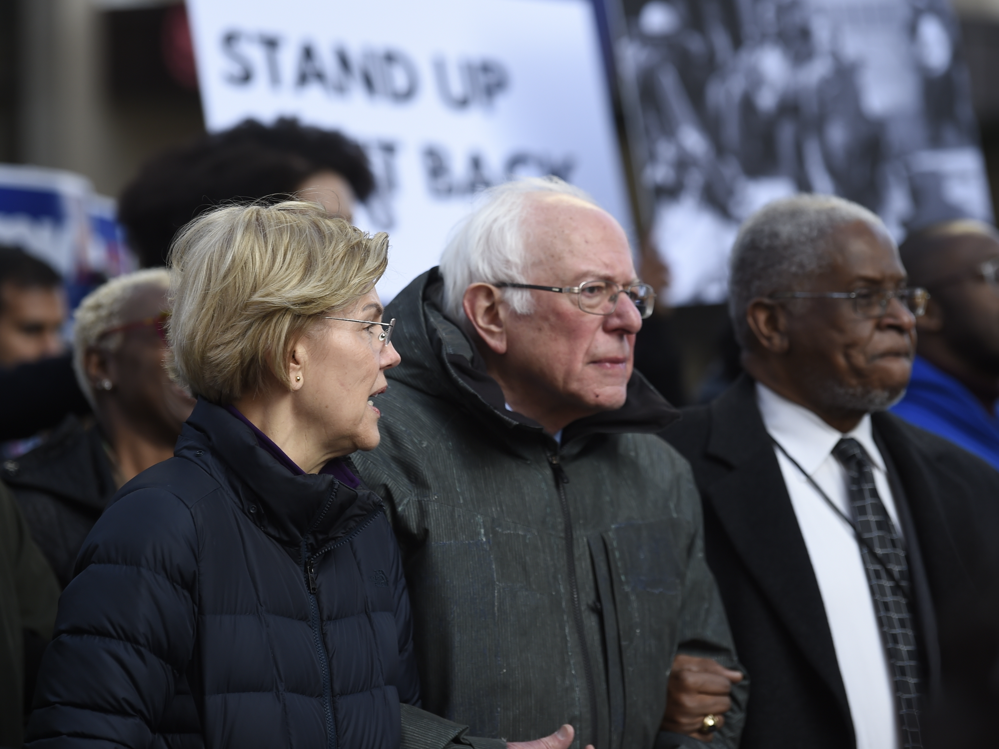 caption: Democratic presidential candidates Elizabeth Warren and Bernie Sanders chat during a Martin Luther King Jr. Day march in January in Columbia, S.C.