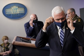 caption: Vice President Pence adjusts his face mask during a news conference with the coronavirus task force at the White House on Thursday.