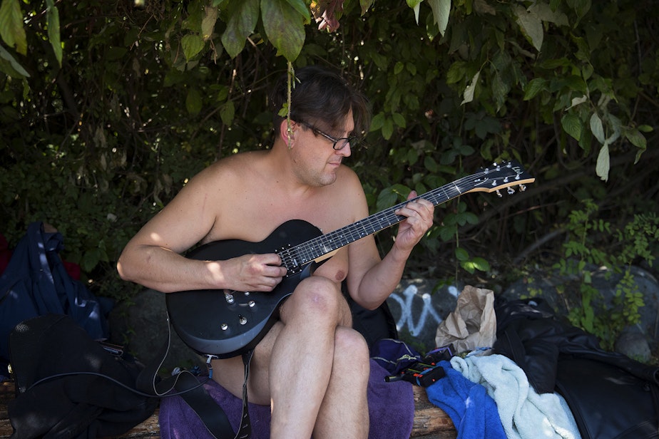 caption: Dan O'Day plays guitar on Monday, August 27, 2018, at Denny Blaine Park in Seattle. 