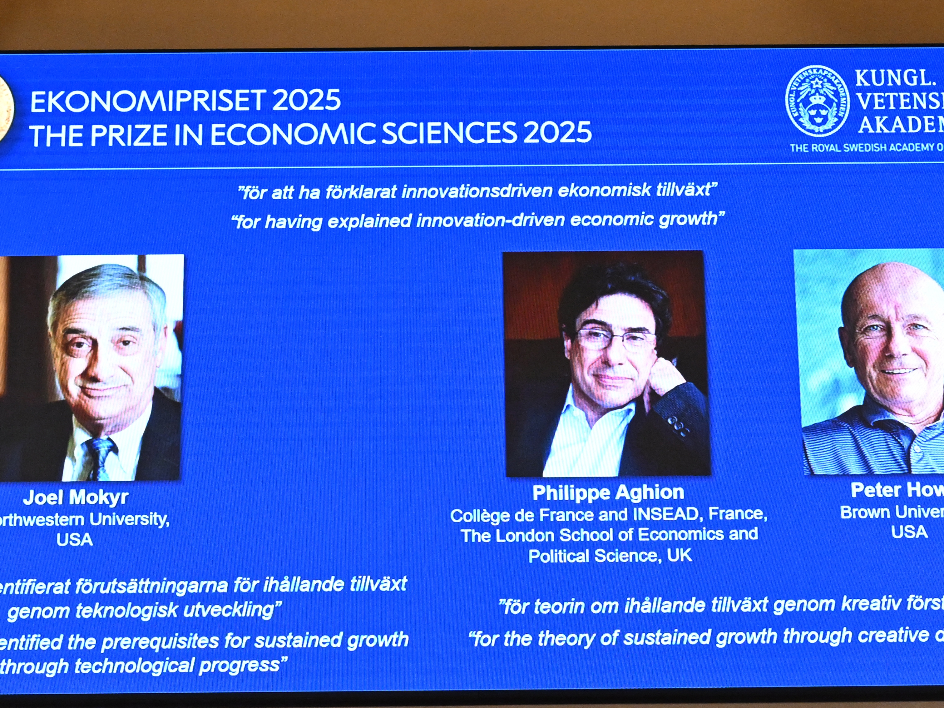caption: From left: A screen shows photos of American-Israeli Joel Mokyr, France's Philippe Aghion and Canada's Peter Howitt during the announcement of the 2025 Nobel Memorial Prize in Economic Sciences at the Royal Swedish Academy of Sciences in Stockholm on Monday.