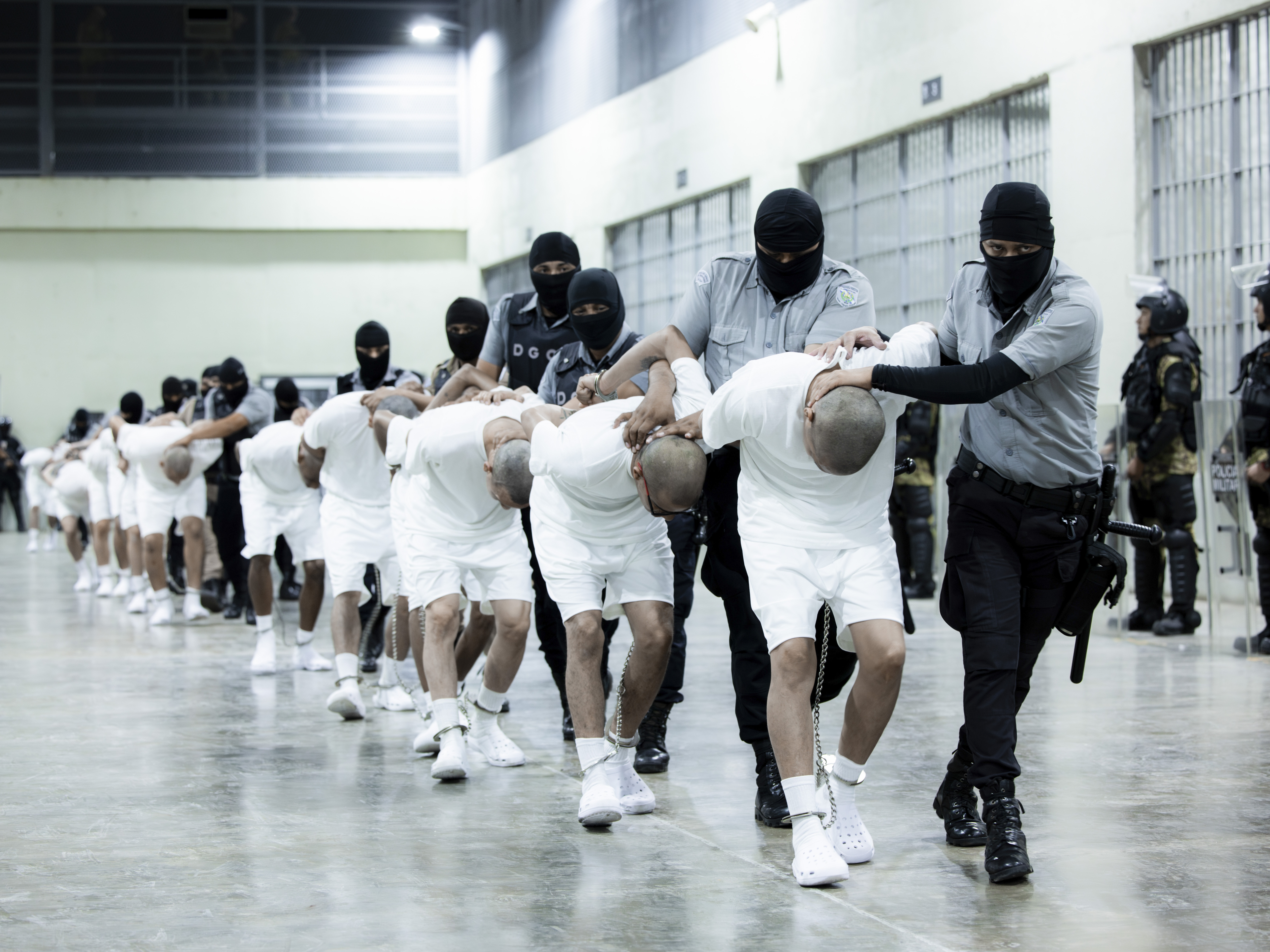 caption: In this photo provided by El Salvador's presidential press office, prison guards transfer deportees from the U.S., alleged to be Venezuelan gang members, to the Terrorism Confinement Center in Tecoluca, El Salvador, Sunday, March 16, 2025.