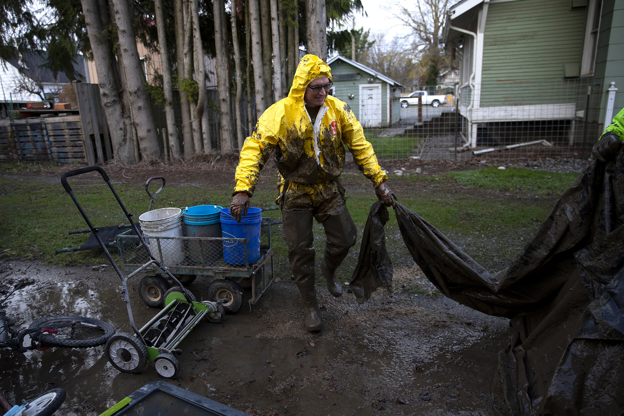 caption: Charlotte Matthew wears PPE while removing the vapor barrier from the crawl space beneath her home following historic flooding, on Wednesday, December 17, 2025, in Sumas. 