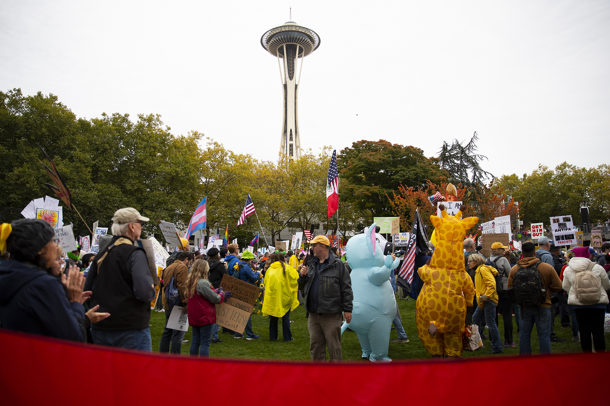 caption: Protesters gather for the No Kings rally at Seattle Center on Saturday, October 18, 2025, in Seattle.