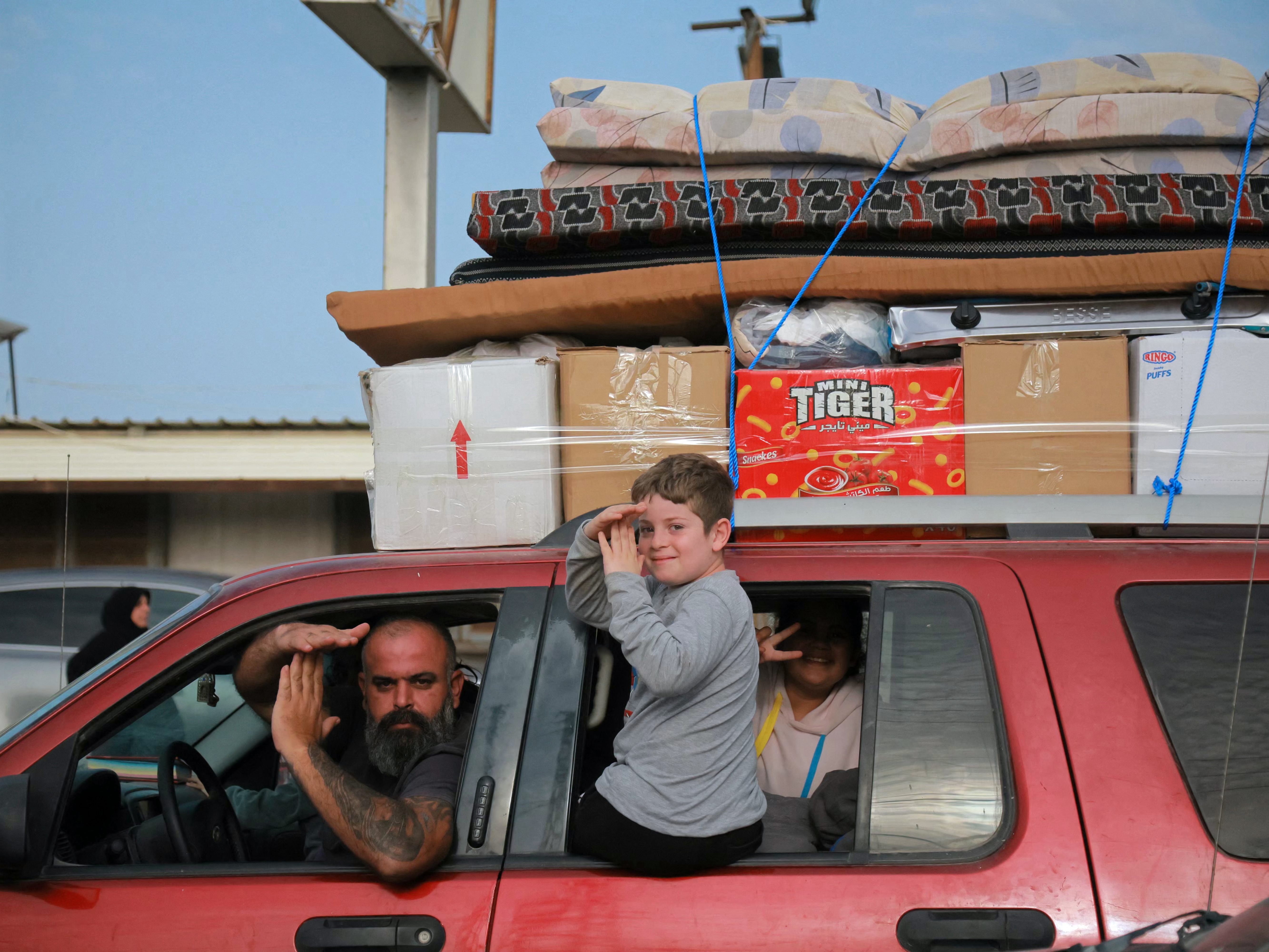 caption: Displaced residents travel through the Qasmieh area as they gesture on the way back to their homes in the southern Lebanon, on Friday, after the start of a 10-day ceasefire deal struck between Lebanon and Israel. Despite the truce, the Israeli military and Hezbollah warned residents not to return to their villages for their own safety.