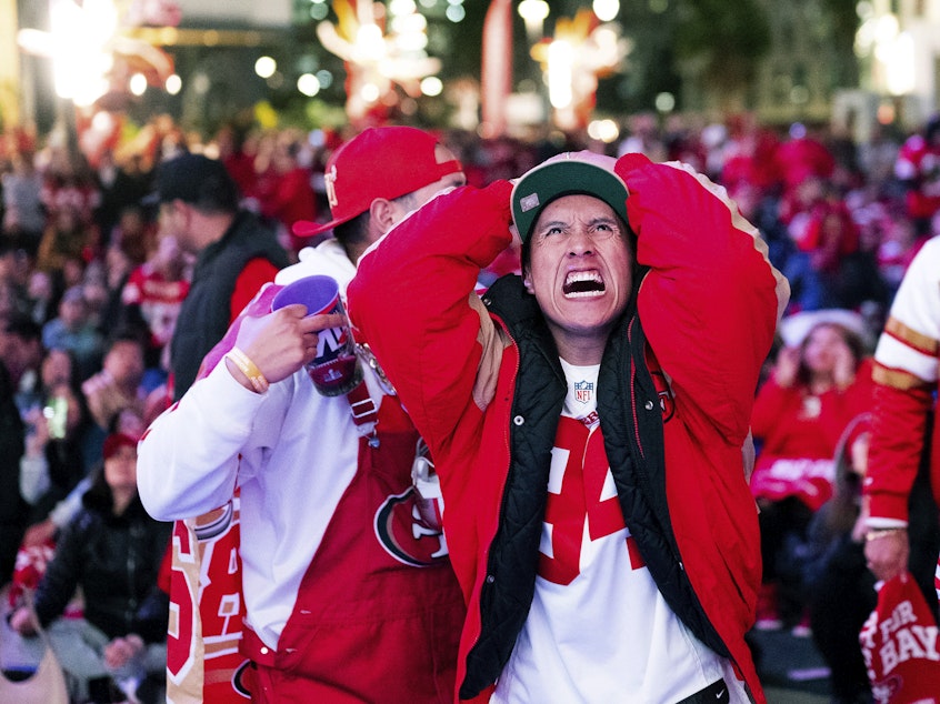caption: A San Francisco 49ers fan reacts while watching a telecast of NFL football's Super Bowl 58 on a screen outside the Chase Center in San Francisco on Sunday, Feb. 11, 2024.