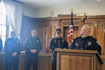 caption: Moscow Police Chief James Fry stands and takes questions at a press conference Friday afternoon in Moscow, Idaho. Police say they’ve apprehended a suspect in the quadruple homicide in the rural college town.  