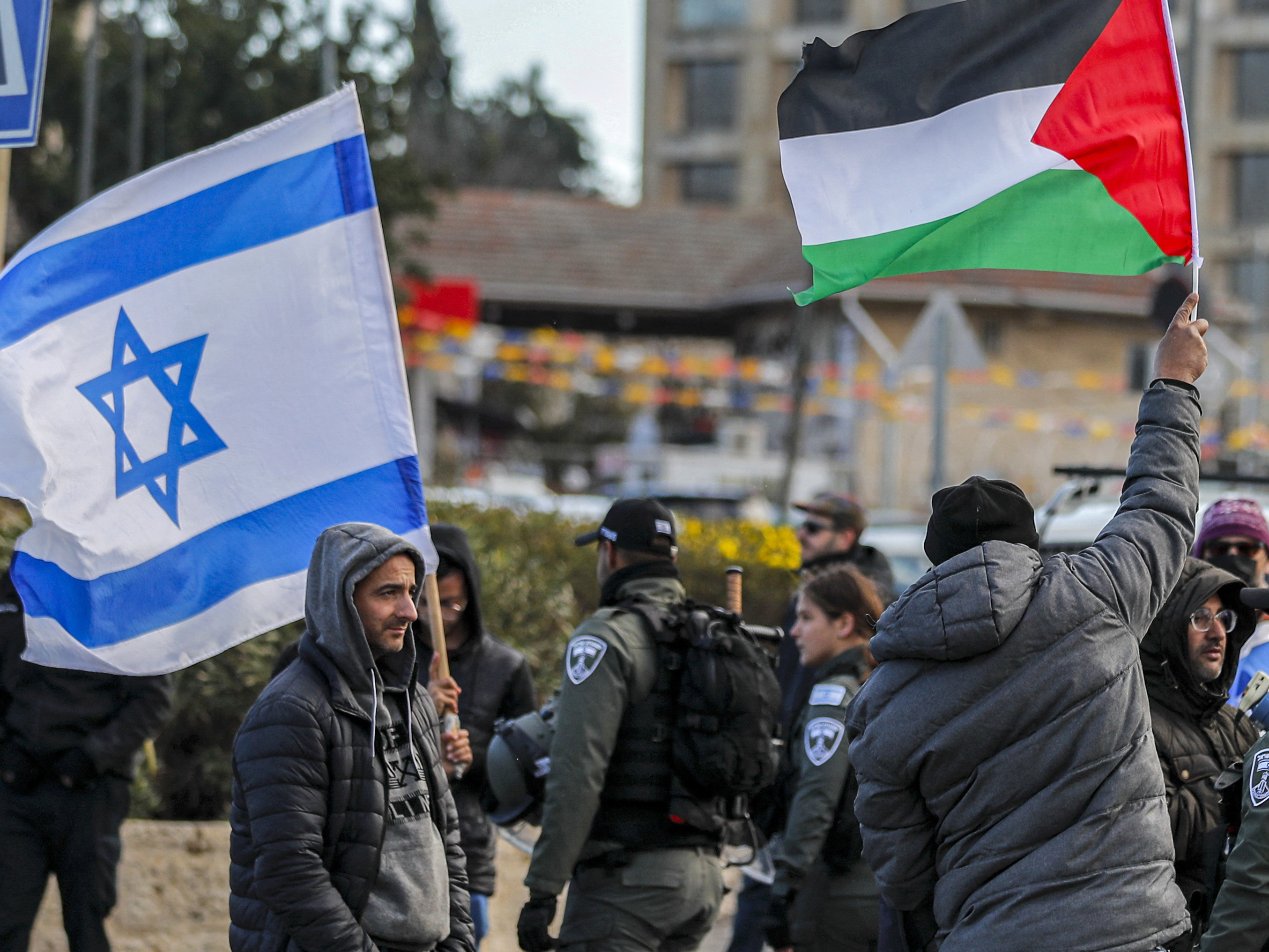 caption: An Israeli settler stands with an Israeli flag before a man holding up a Palestinian flag during a demonstration in the East Jerusalem neighborhood of Sheikh Jarrah in February 2022.