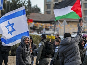 caption: An Israeli settler stands with an Israeli flag before a man holding up a Palestinian flag during a demonstration in the East Jerusalem neighborhood of Sheikh Jarrah in February 2022.