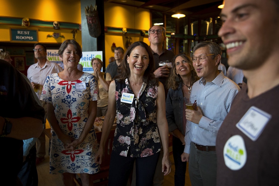 caption: Seattle city council candidate in the 6th district Heidi Wills, center, smiles at her campaign manager, Alex Wenman, right, after the first election results came in on Tuesday, August 6, 2019, at Hales Ales in Seattle.  