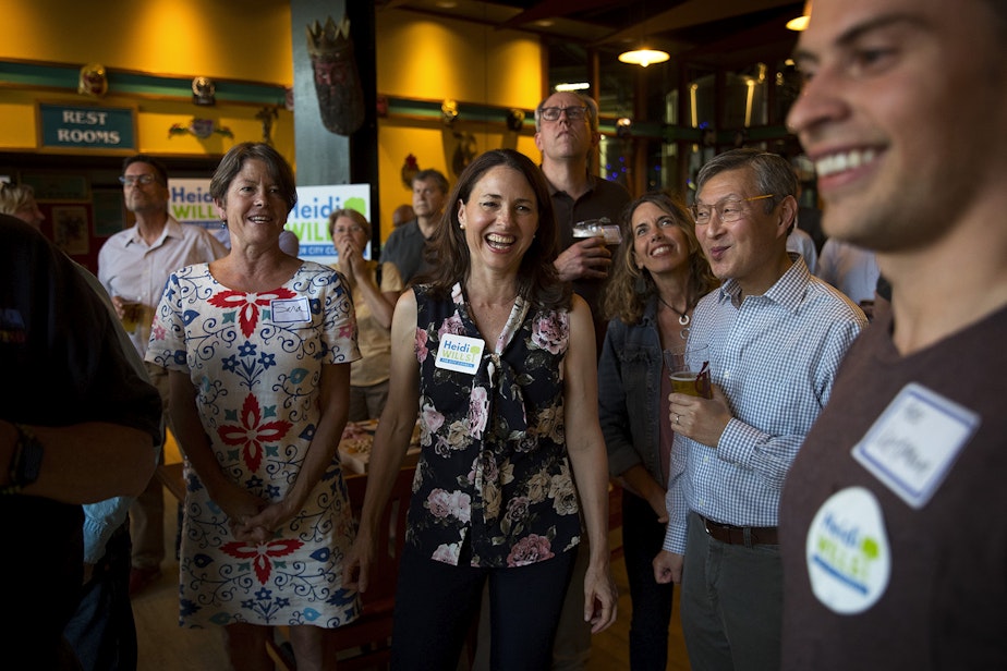 caption: Seattle city council candidate in the 6th district Heidi Wills, center, smiles at her campaign manager, Alex Wenman, right, after the first election results came in on Tuesday, August 6, 2019, at Hales Ales in Seattle.