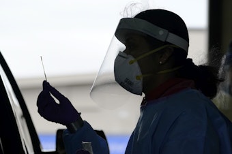 caption: A University of Washington research coordinator holds up a swab after testing a someone for coronavirus on Oct. 23 in Seattle. The U.S. recorded a record high number of new daily cases Friday.
