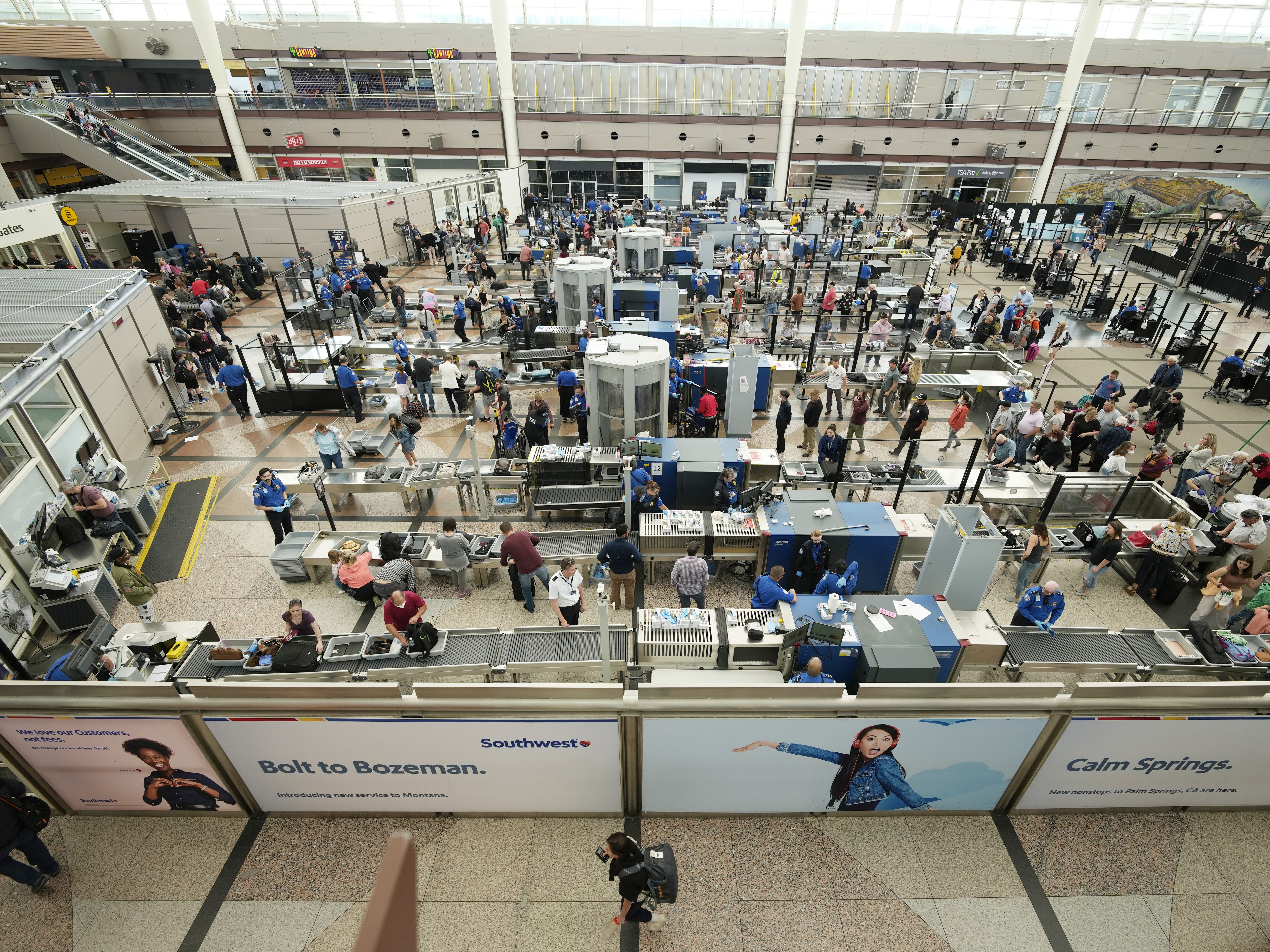caption: Travelers queue up at a security checkpoint in the main terminal of Denver International Airport on Thursday.