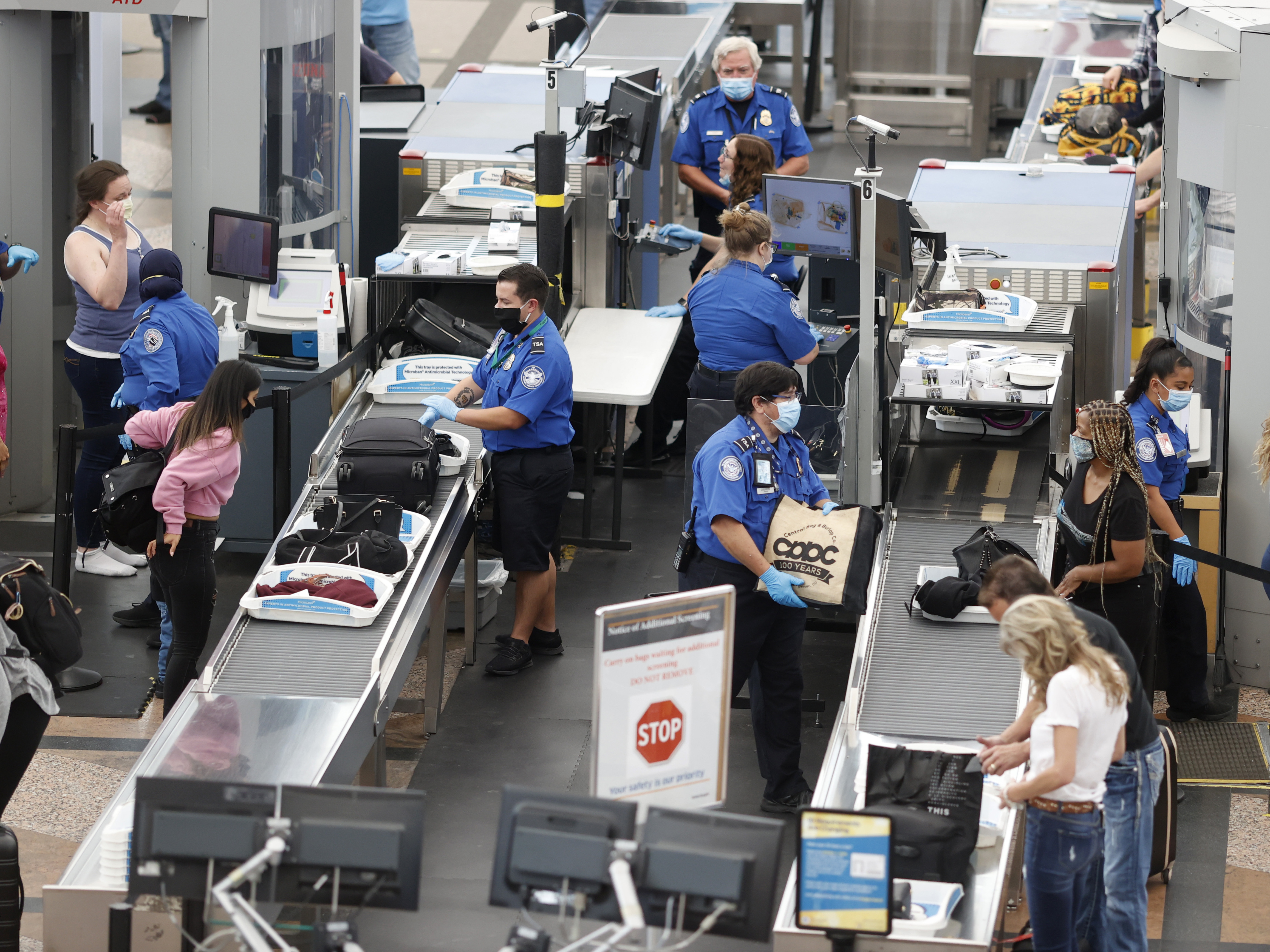 caption: TSA agents clearing passengers at Denver International Airport, June 2020. TSA found twice as many weapons on passengers per million in 2020 than they did the year prior.