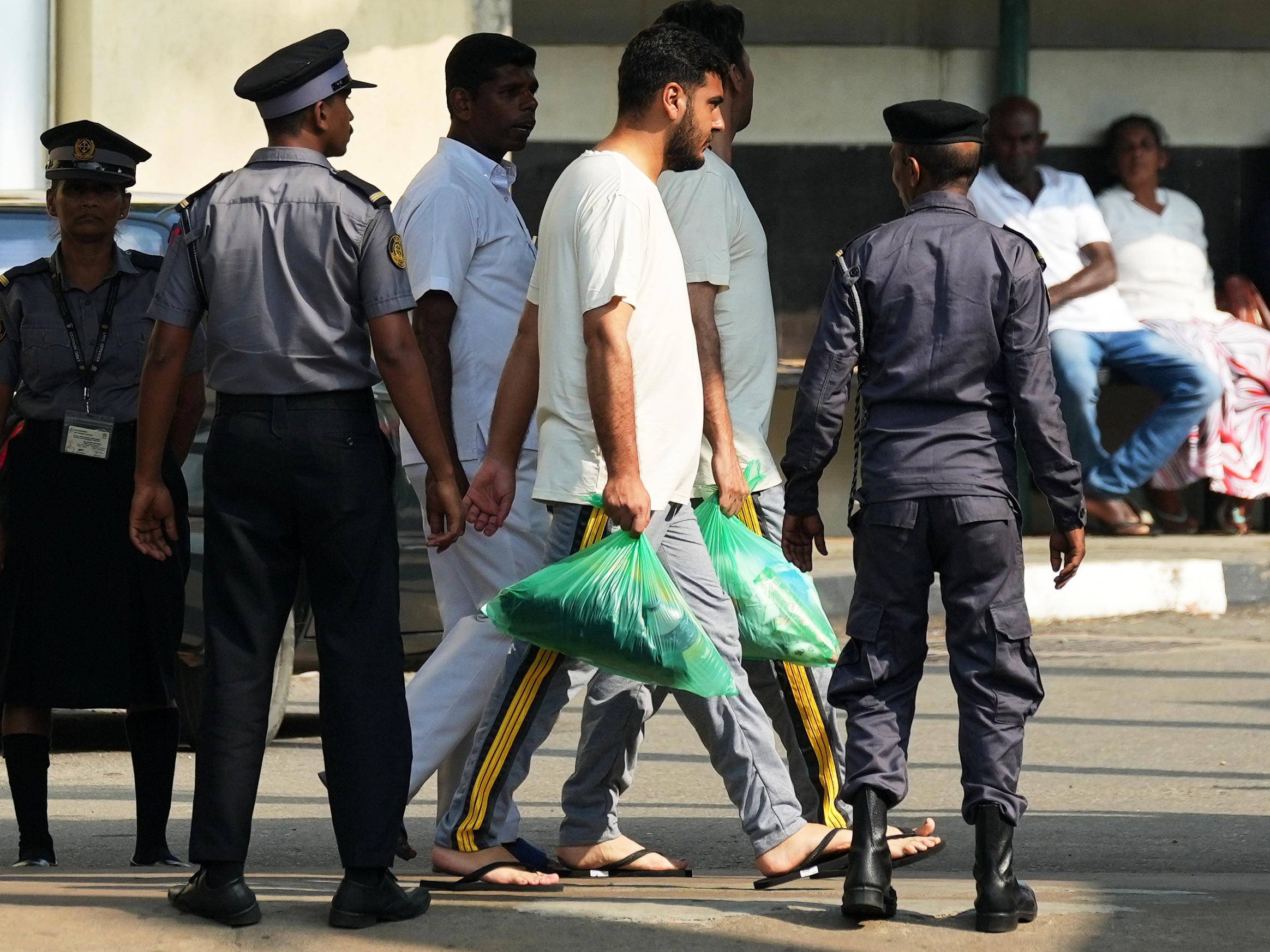 caption: Two Iranian sailors, center, who were rescued from IRIS Dena warship by Sri Lanka's navy are escorted to a Judicial Medical Officer from the National Hospital, in Galle, Sri Lanka, Thursday, March 5, 2026. (AP Photo/Eranga Jayawardena)