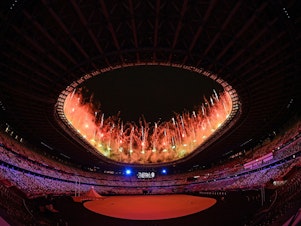 caption: Fireworks go off around the Olympic Stadium during the opening ceremony of the Tokyo 2020 Olympic Games, in Tokyo, on July 23, 2021.