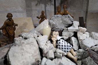 caption: A view of the Evangelical Lutheran Christmas Church's Nativity scene in Bethlehem. This year, it portrays a baby Christ born under rubble and wrapped up in a Palestinian <a href="https://www.npr.org/2023/12/06/1216150515/keffiyeh-hamas-palestinians-israel-gaza">keffiyeh</a>.
