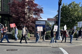 caption: Members of International Brotherhood of Electrical Workers Local 46 picket outside the National Electrical Contractors Association office in Shoreline, Washington, on June 6, 2024.