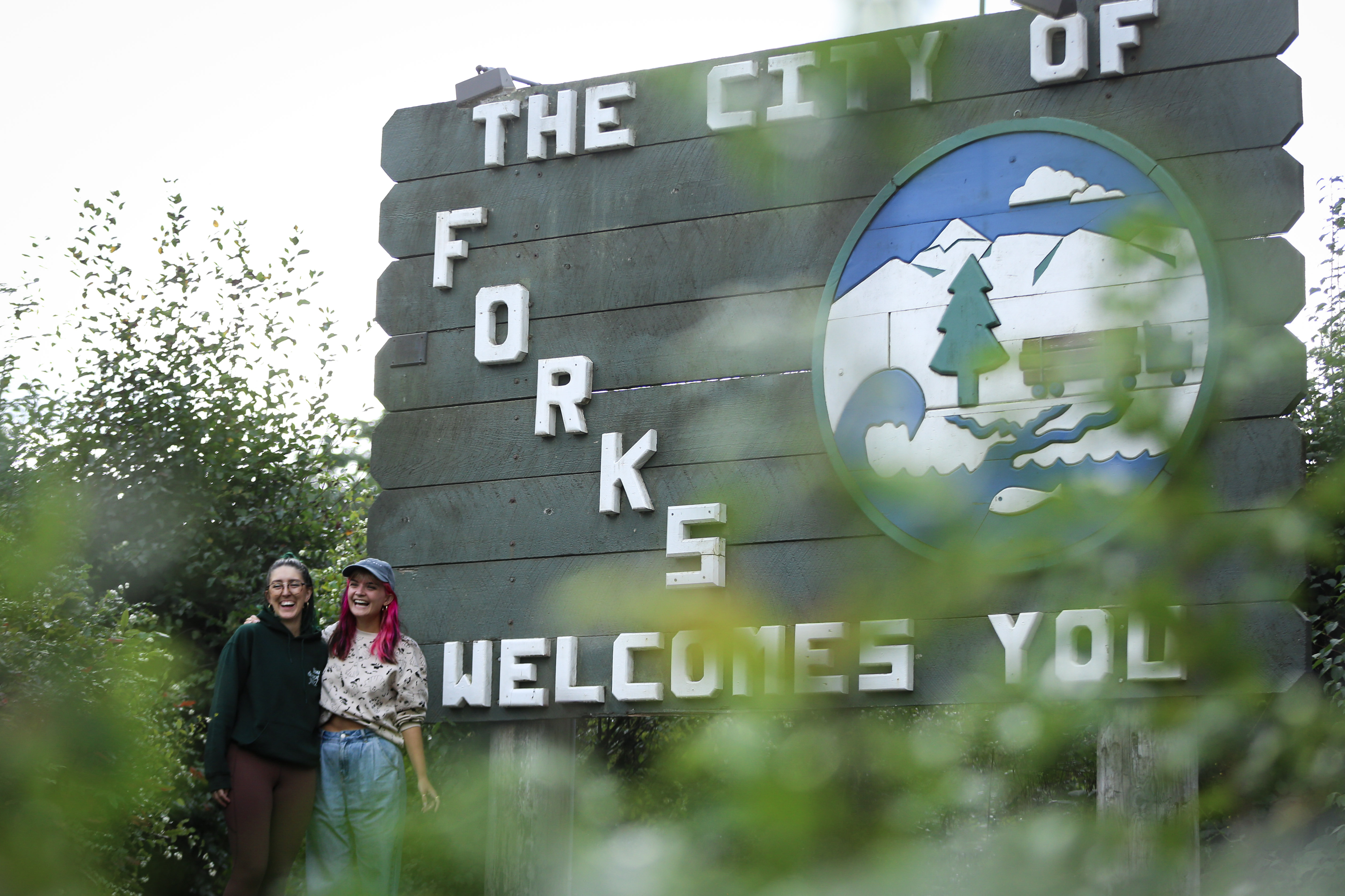 caption: Taylor (left) and Brige (right) from Brisbane, Australia, are seen in front of the sign that welcomes visitors to the city of Forks, Washington. People came from all over to celebrate the 20th anniversary of the "Twilight" series, which takes place in the town.