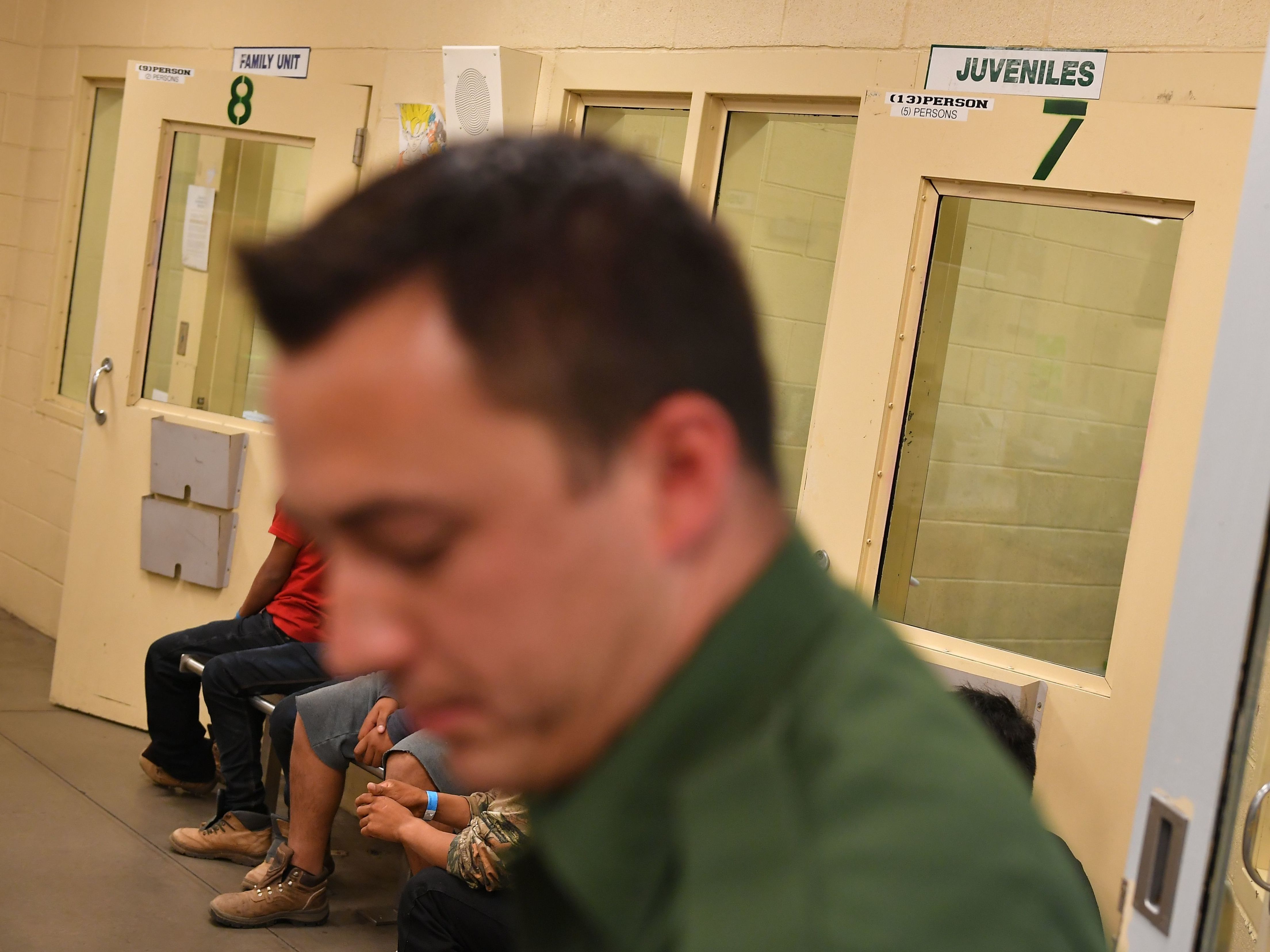 caption: In this file photo, young migrants, whose faces cannot be shown, sit inside a U.S. Customs and Border Protection Facility in Tucson, Arizona.