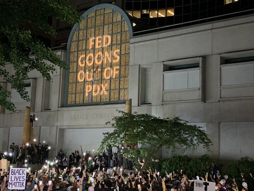 caption: At the Multnomah County Justice Center in Portland, a projected image reads "Fed Goons Out of PDX"