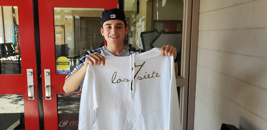 caption: Victor Campos outside of Chinook Middle School with his seventh anniversary Los Siete hoodie.