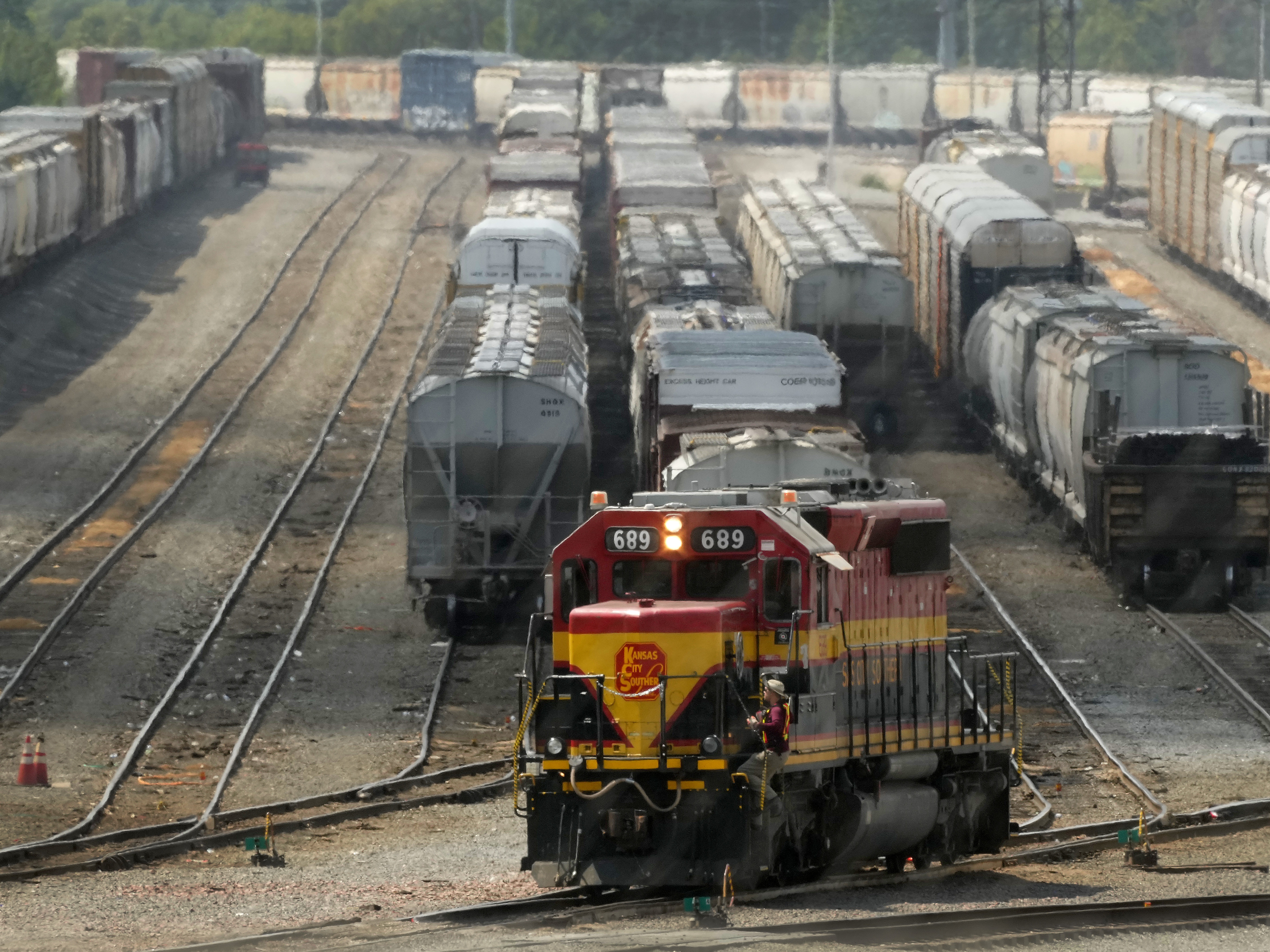 caption: A worker climbs aboard a locomotive at a CPKC rail yard on Wednesday, Aug. 21, 2024, in Kansas City, Mo.