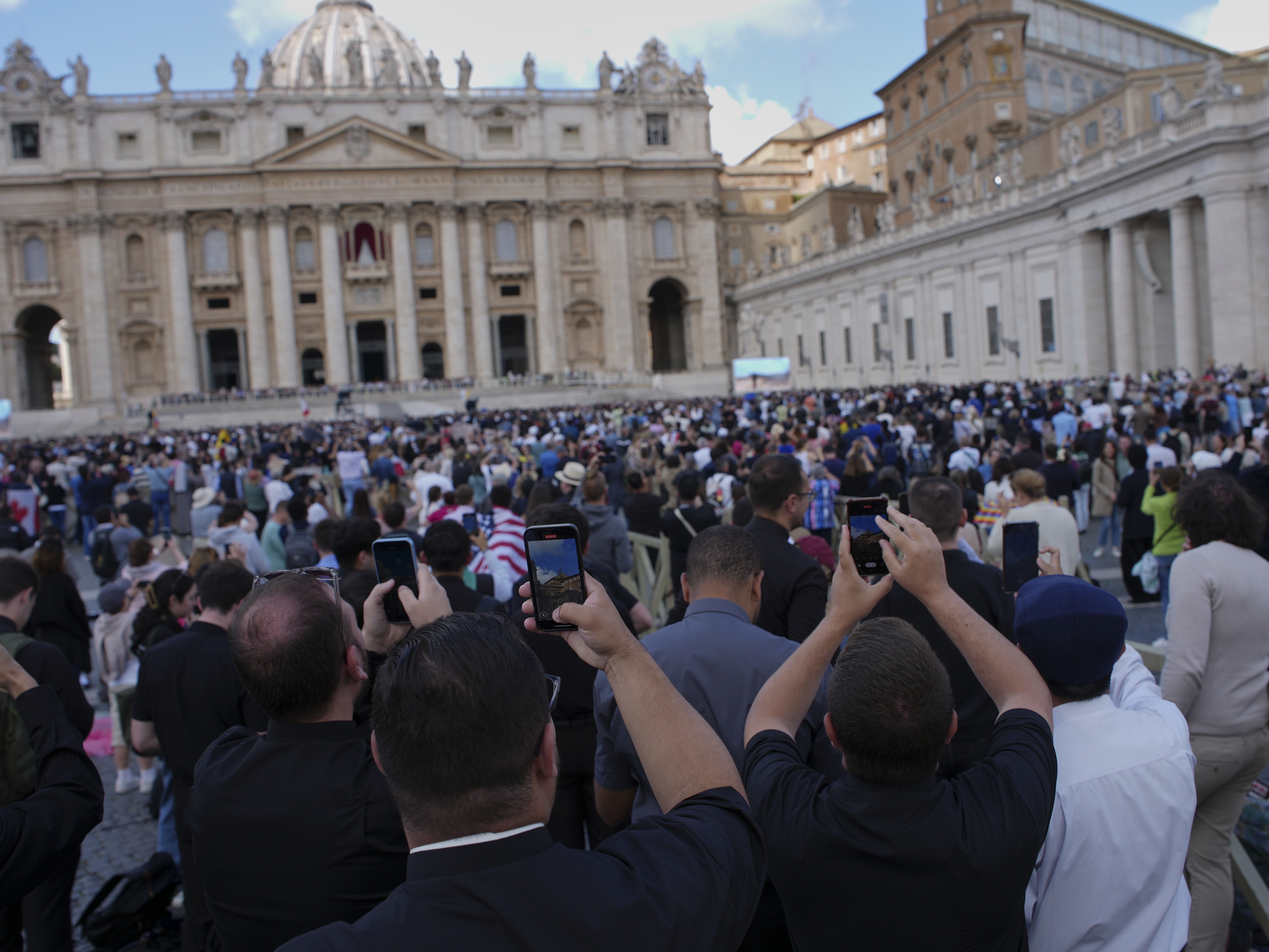 caption: Faithful take photos as black smoke billows from the Sistine Chapel during the conclave to elect a new pope at the Vatican on Thursday.