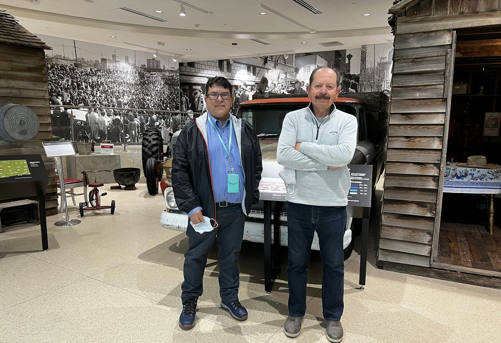 Dr. Jerry Garcia (left) and Dr. Erasmo Gamboa (right) at Sea Mar Museum of Chicano/a and Latino/a culture, in South Park. Behind them are cabins from Sunnyside, WA, which were previously housing for agricultural workers.