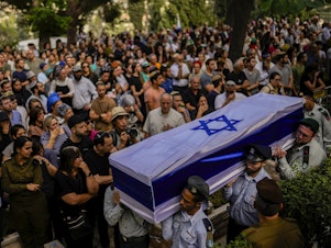 caption: Israeli soldiers carry the flag-covered coffin of a person killed in the Hamas attack earlier this month. Rabbis and reservists have worked around the clock at a military base in Israel to identify and count the dead.