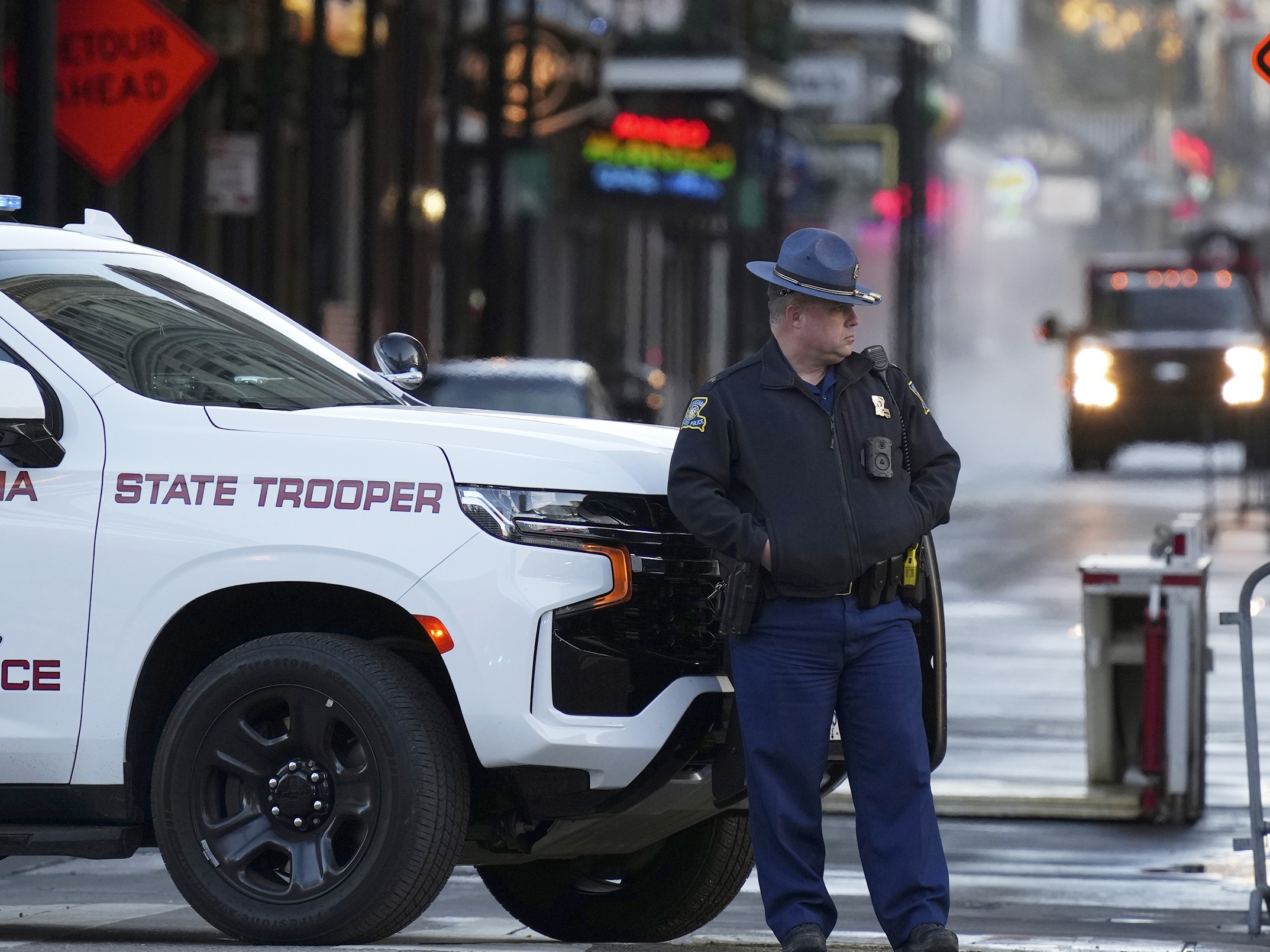 caption: A state trooper stands by New Orleans' Canal and Bourbon streets on Thursday, the day after a truck slammed into a crowd on Bourbon Street, killing at least 14 people.
