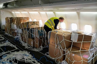 caption: A volunteer straps down boxes of medical supplies bound for Ukraine on Monday, March 28, 2022.