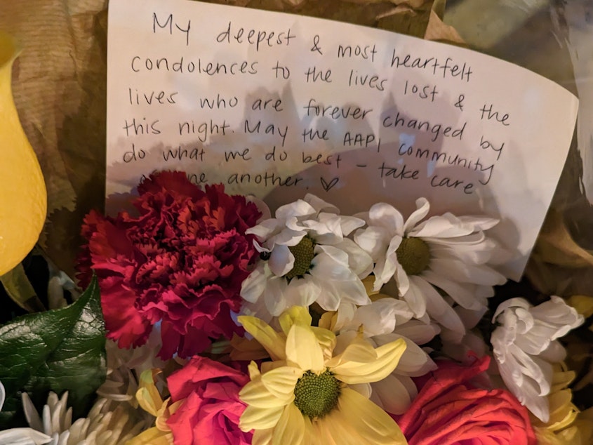 caption: Makeshift vigils of candles, flowers and notes started to appear on Sunday after the shooting. One note read "My deepest [and] most heartfelt condolences to the lives lost [and] the lives who are forever changed by this night. May the AAPI community do what we do best — take care of one another."