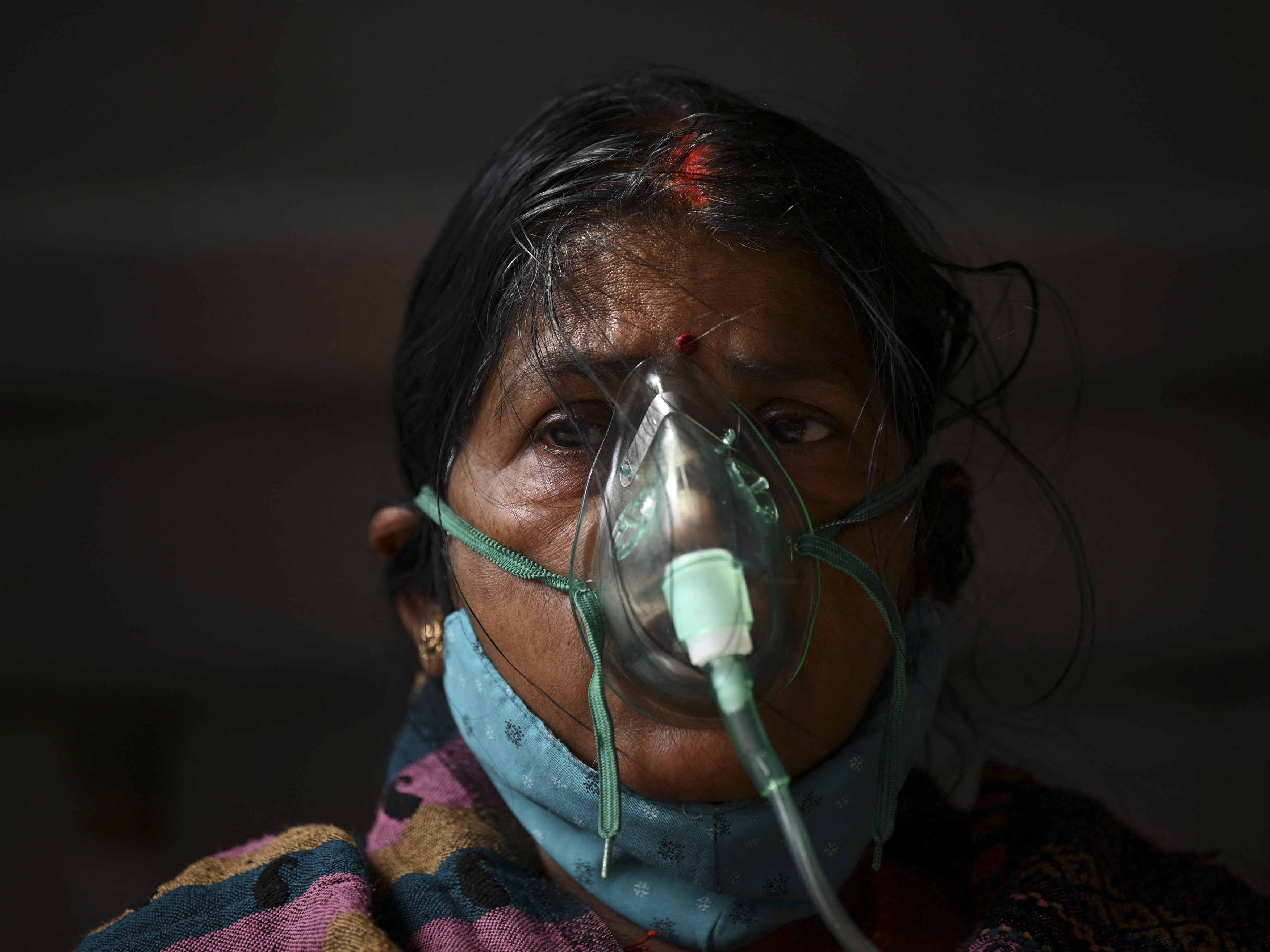 caption: A patient breathes with the help of oxygen provided at a tent installed at a gurdwara, a place of worship for Sikhs, in Ghaziabad, India, on May 2.