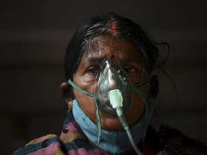 caption: A patient breathes with the help of oxygen provided at a tent installed at a gurdwara, a place of worship for Sikhs, in Ghaziabad, India, on May 2.