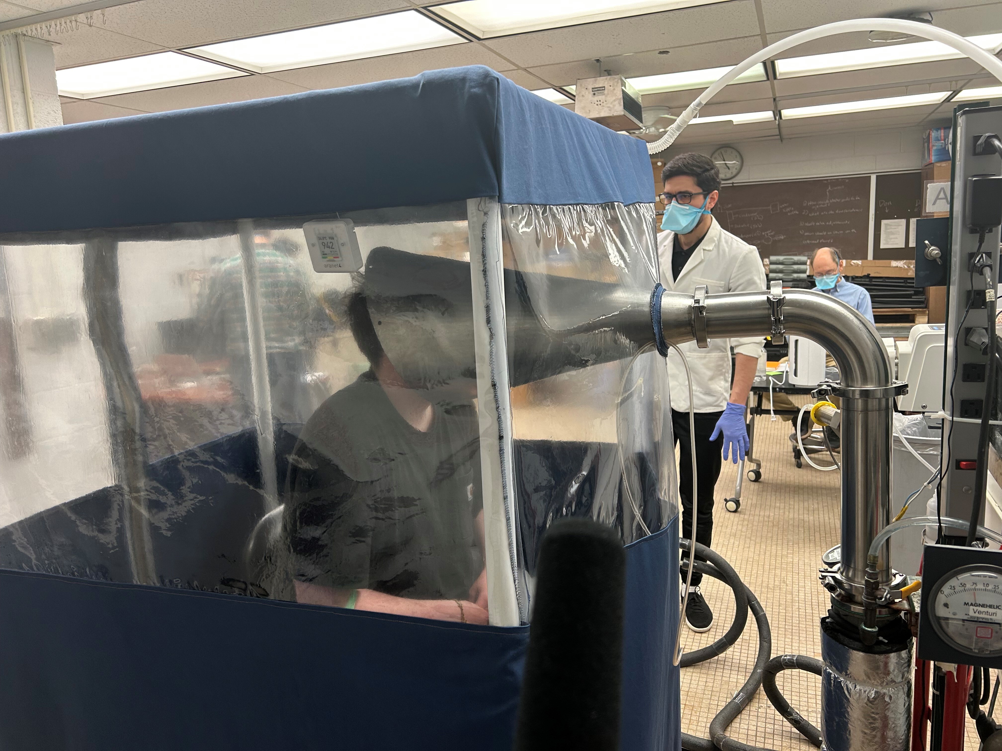 caption: A person breathes inside the Gesundheit II, a machine that allows scientists to study the behavior of pathogens when they're exhaled. Research like this is at risk amid the Trump administration's proposed funding cuts.