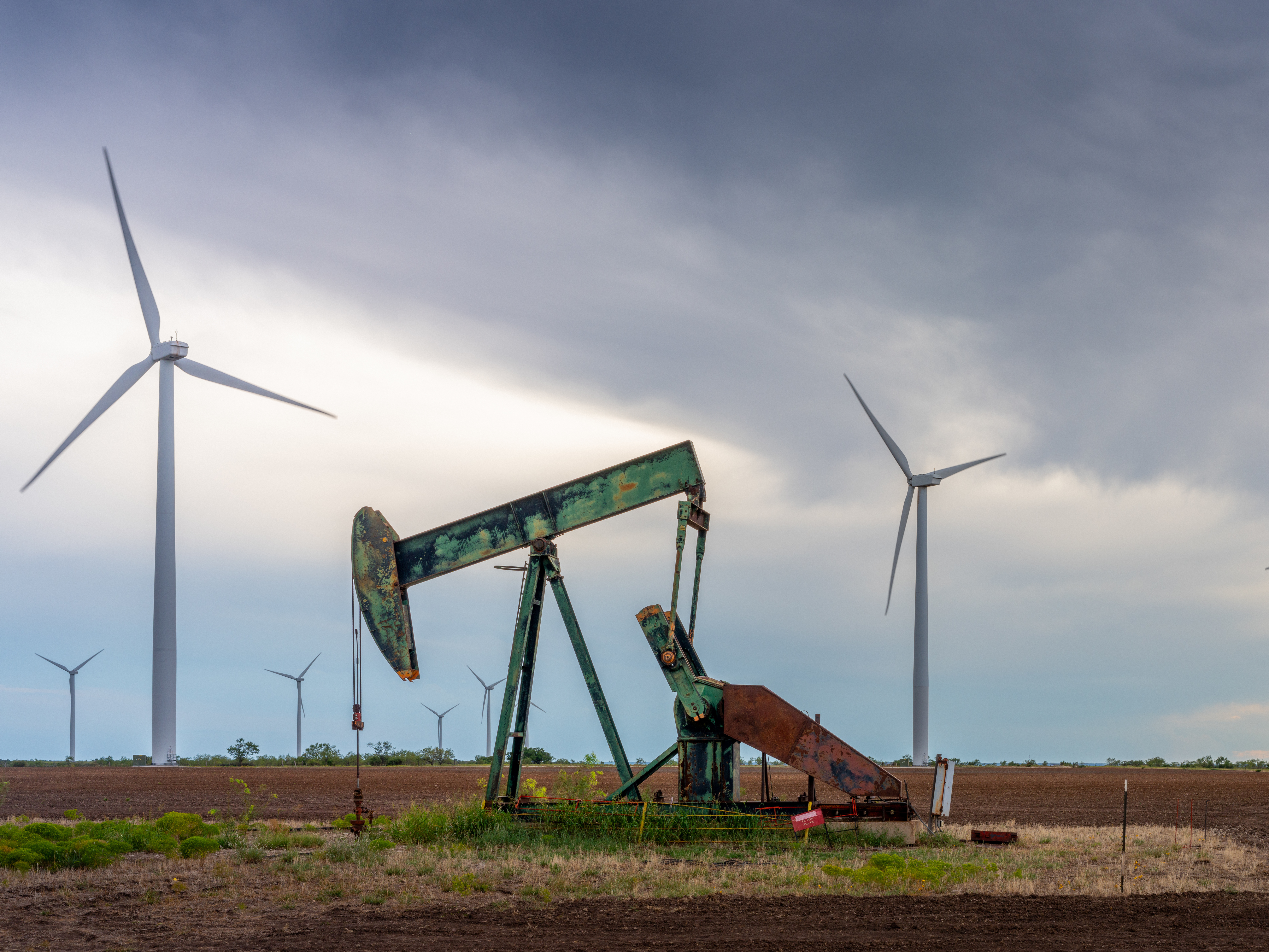 caption: An oil pump jack stands near a field of wind turbines in Nolan, Texas, on Oct. 4. Oil companies are under pressure to pivot more swiftly toward renewable energy. Here's one reason why that's not happening so quickly: It's still incredibly lucrative to sell oil.