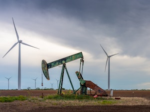 caption: An oil pump jack stands near a field of wind turbines in Nolan, Texas, on Oct. 4. Oil companies are under pressure to pivot more swiftly toward renewable energy. Here's one reason why that's not happening so quickly: It's still incredibly lucrative to sell oil.